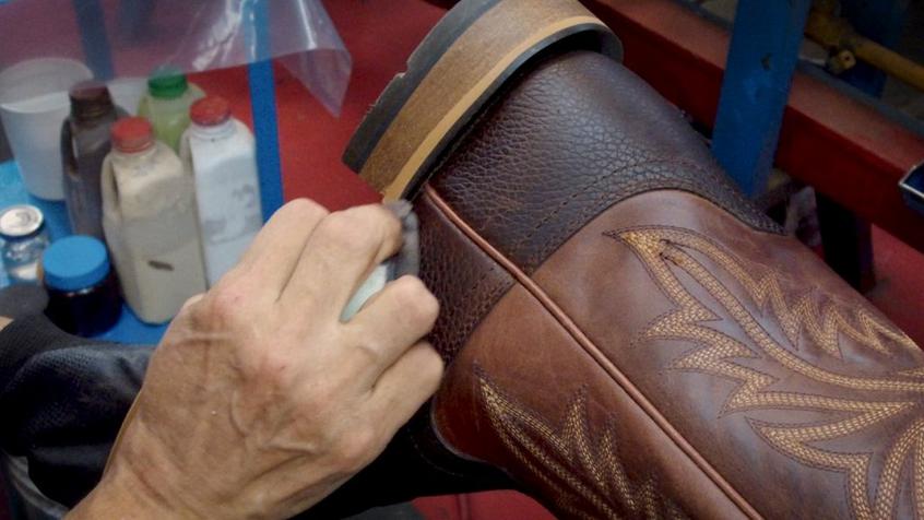 man polishing leather cowboy boot